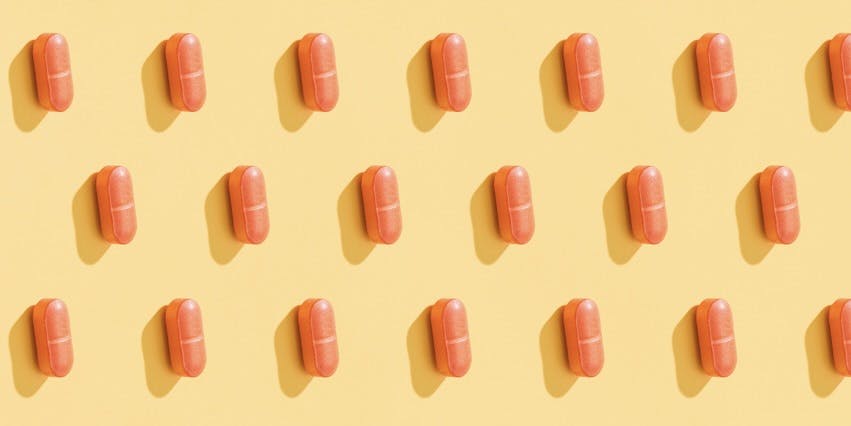 A repeating pattern of orange pills on a lemon yellow background